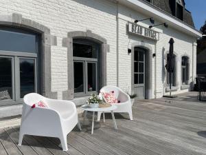 2 chaises et une table en face d'un bâtiment dans l'établissement Gîte de charme bord de Meuse, à Namur