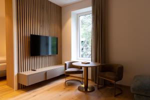 Habitación con mesa, 2 sillas y TV. en Luxury Apartment Villa Ortler, en Merano