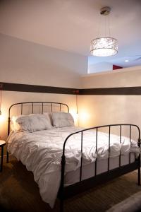 a bedroom with a bed with white sheets and a chandelier at New Spacious Studio Suite with Mountain Views in Kamloops