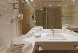 un bagno con un lavandino e un grande specchio di Kim Hotel Dresden a Dresda