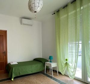 een slaapkamer met een groen bed en een raam bij Appartamento Via Rieti in Senigallia