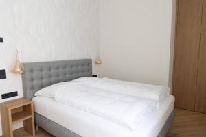 1 dormitorio con 1 cama con sábanas blancas y mesa en Luxury Apartment Villa Ortler, en Merano