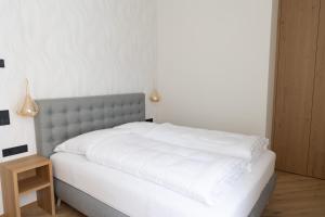 Un dormitorio con una cama con sábanas blancas y una mesa. en Luxury Apartment Villa Ortler, en Merano