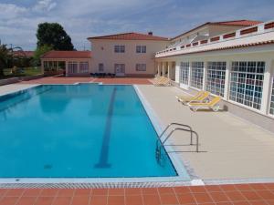 ein großer Pool mit Stühlen und ein Gebäude in der Unterkunft Quinta de Malmedra in Santiago do Cacém