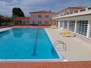 a large swimming pool with chairs and a building at Quinta de Malmedra in Santiago do Cacém