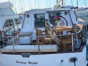 a boat with a wooden table and chairs on it at Sailing Nights Boat&breakfast in Alghero