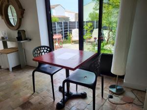 1 mesa y 2 sillas en una habitación con ventana en Ma Chambre d'Amis en Saint-Clément-des-Baleines