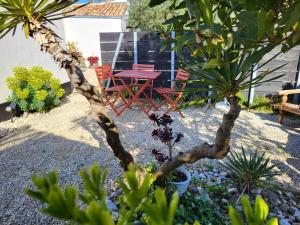 a red chair and a table in a garden at Ma Chambre d'Amis in Saint-Clément-des-Baleines