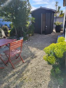 a bench and a table in a garden with a shed at Ma Chambre d'Amis in Saint-Clément-des-Baleines