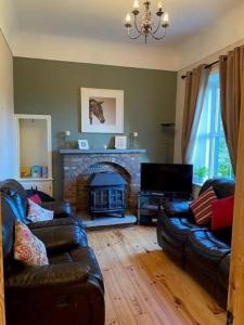 a living room with two leather couches and a fireplace at Beechwood View in Kilrush