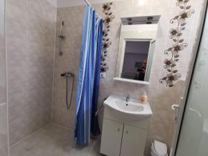 a bathroom with a blue shower curtain and a sink at Fitness House with garden in Constanţa +38 photos
