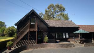 a log cabin with a table and an umbrella at Paddock Barn ~ Short & Long term stay, pets welcome ~ Woodbridge, Framlingham ar in Cretingham