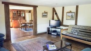 a living room with a couch and a tv at Paddock Barn ~ Short & Long term stay, pets welcome ~ Woodbridge, Framlingham ar in Cretingham