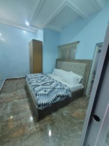 um quarto com uma cama num quarto azul em Dazzle Hotels and Apartments em Jidu