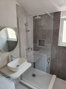 a bathroom with a shower and a sink and a mirror at Apartments Radić in Rogoznica