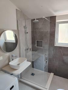 a bathroom with a shower and a sink and a mirror at Apartments Radić in Rogoznica