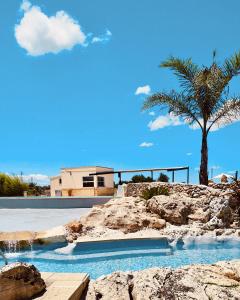 a swimming pool with a palm tree and a house at Agriturismo Le Site in Corigliano dʼOtranto