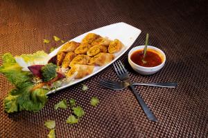 a plate of food with a salad and dipping sauce at Hotel Millennium Inn, Prayagraj in Allahābād
