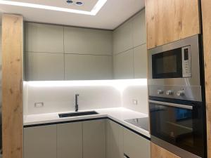 a white kitchen with a microwave and a stove at Don Bosko Cozy Heaven Apartments 2 in Tirana