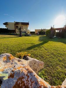 ein Fels im Gras mit einem Gebäude im Hintergrund in der Unterkunft Casa Vacanze Il Sole in Casamassella