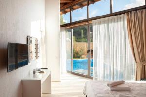 a bedroom with a bed and a large window with a pool at Villa Alaçatı (İslamlar-Kalkan) in Kaş