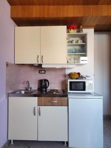 a kitchen with white cabinets and a microwave at Apartmani Daria & Jure in Trogir