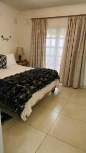 a bedroom with a bed with a black blanket on it at La Lucia Sleepover in Durban