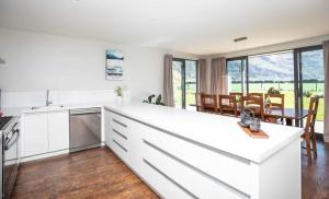 uma cozinha com armários brancos e uma sala de jantar com uma mesa em Matukituki Lodge em Wanaka