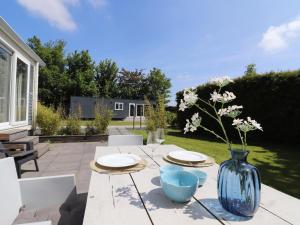 赫勞的住宿－Modern chalet in Grou with a spacious garden in a beautiful location，一张桌子上放有盘子和蓝色花瓶