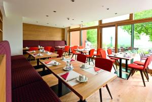 a restaurant with wooden tables and red chairs at Achalm Hotel in Reutlingen