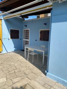 un patio con mesa y sillas en una pared azul en La Casetta delle sirene Anzio en Anzio