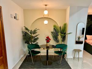a dining room with a table and two green chairs at The Fjord at Libi Apartment in Accra