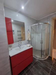 ein Bad mit einem roten Waschbecken und einer Dusche in der Unterkunft Feels like home. in Koukounariá