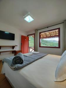 a bedroom with a large white bed with a window at Recanto Serra do Trovão in Ouro Preto