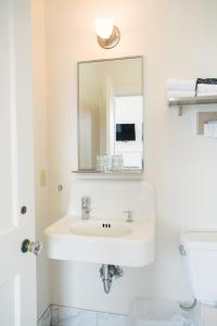 Baño blanco con lavabo y espejo en Selina Commodore Astoria, en Astoria, Oregon