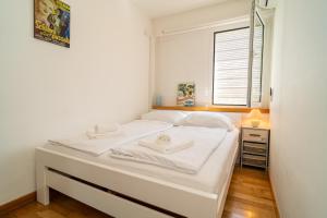 a small bedroom with a white bed and a window at Apartment Cosmopolitan in Zadar