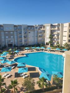 莫納斯提爾的住宿－Palm Lake Resort Folla Monastir vue Piscine，享有带椅子和遮阳伞的游泳池的上方景色