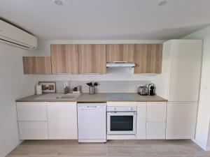 una cocina con electrodomésticos blancos y armarios de madera en Appartement Le Pradet - Résidence Piscine Tennis Bord de Mer - Bertrand Béatrice, en Le Pradet