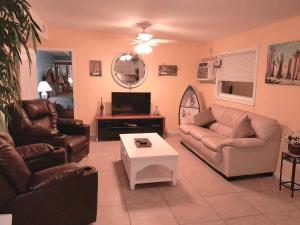 a living room with two couches and a tv at Susan and Ledif's Tropical Hideaway in Greenacres City