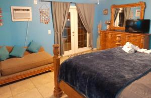 a bedroom with a bed and a couch and a mirror at Susan and Ledif's Tropical Hideaway in Greenacres City