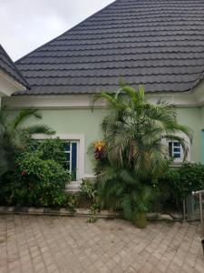 a house with a palm tree in front of it at Dazzle Hotels and Apartments in Jidu