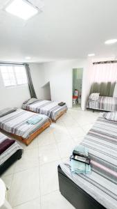 3 camas en una habitación con suelo de baldosa blanca en Pretty View Posada, en San Andrés