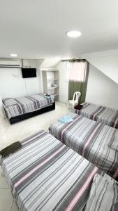 una habitación con 3 camas y una silla. en Pretty View Posada, en San Andrés