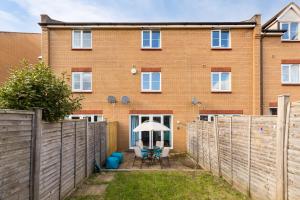 a house with a fence and a table with an umbrella at Spacious Group House for Contractors & Families - Ensuites, Parking & Netflix by DreamyPads in Bristol