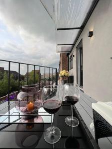 zwei Gläser Wein auf einem Tisch auf einem Balkon in der Unterkunft Queens Apartment ( Entire 2 bed apartment ) in Potters Bar
