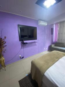 ein Schlafzimmer mit einer lila Wand mit einem Bett und einem TV in der Unterkunft Copacabana Studio in Rio de Janeiro