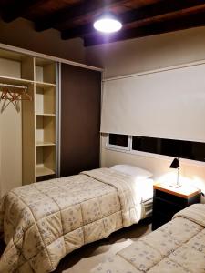 聖卡洛斯－德巴里洛切的住宿－PH Design Entre Pinos，一间卧室设有两张床和一张桌子上的台灯。