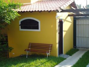 カボ・フリオにあるVila do Sossegoの黄色い建物前に座るベンチ