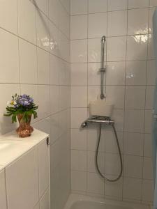 a white tiled shower with a hose in a bathroom at Zelte individuell auf der Obstwiese in Dippoldiswalde