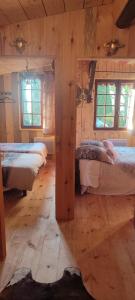 um quarto com 3 camas num chalé de madeira em Domaine le lanis "cabane de Pauline" em Saint-Girons